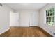 Bright bedroom features hardwood floors and a large window with green views and bi-fold closet doors at 5630 Lake Forrest Dr, Sandy Springs, GA 30342