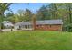 Lovely brick home featuring a sunroom, well-maintained lawn, and mature trees creating a serene outdoor space at 5630 Lake Forrest Dr, Sandy Springs, GA 30342