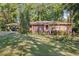 Charming brick home with red shutters and a spacious front yard, surrounded by mature trees at 4535 Forest Green Dr, Sugar Hill, GA 30518