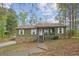 Charming single-story home featuring a stone foundation and inviting front porch, nestled among mature trees at 6909 Heritage Pl, Acworth, GA 30102