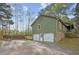 View of a three-door garage with green siding, stone accents, and a basketball hoop on the side of the driveway at 6909 Heritage Pl, Acworth, GA 30102