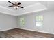 Spacious main bedroom with wood-look floors, neutral walls, tray ceiling, and a ceiling fan at 2590 Carolina Rdg, Riverdale, GA 30296