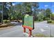 A welcoming entrance sign for The Woods Condominiums amidst a lush, green landscape on a sunny day at 2929 Torreya Se Way, Marietta, GA 30067