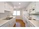Well lit, clean kitchen with stainless steel sink, white cabinetry, white appliances, and hardwood floors at 2929 Torreya Se Way, Marietta, GA 30067