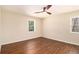 Bright bedroom featuring hardwood floors, a modern ceiling fan, and two windows overlooking the outdoors at 9640 Cedar Grove Rd, Fairburn, GA 30213