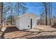 A small white outbuilding with a metal door sits on a leaf covered lot at 9640 Cedar Grove Rd, Fairburn, GA 30213