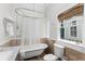 Elegant bathroom featuring a claw-foot tub, tan tiled walls, and a window with custom blinds at 966 Blue Ridge Ne Ave, Atlanta, GA 30306
