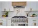 Close-up of a stainless steel range with custom vent hood and white cabinets, accented with gold hardware at 1456 S Gordon Sw St, Atlanta, GA 30310