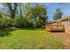 A large green lawn and mature trees surround brick home with wooden deck at 2877 Kensington Way, Rex, GA 30273