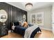 Modern bedroom featuring a black accent wall, a crystal chandelier, and a bright window with outside views at 1004 Windermere Xing, Cumming, GA 30041