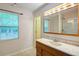 Bright bathroom featuring a large window, wooden cabinets, and framed mirror with vanity lights at 1315 Bustling Sw Ln, Marietta, GA 30064