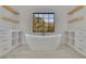 Bright bathroom featuring a large soaking tub, dual vanities, and floating shelves for storage at 2875 Caney Parc Way, Cumming, GA 30041