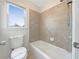 Bright bathroom featuring tiled walls surrounding the tub and natural light from the window at 2123 Tigger Ne Trce, Marietta, GA 30066