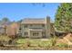 A backyard view of a two-story home with a light green exterior, a chimney, and a patio at 3707 Mcguire Nw St, Kennesaw, GA 30144
