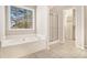Bright bathroom featuring a large soaking tub, shower, and organized closet at 3707 Mcguire Nw St, Kennesaw, GA 30144
