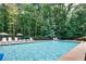 Sparkling community pool surrounded by mature trees with lounge chairs and umbrellas at 3707 Mcguire Nw St, Kennesaw, GA 30144