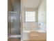 Bright bathroom featuring a soaking tub with white tile surround and a glass-enclosed shower at 4097 Rosebud Park Dr, Snellville, GA 30039