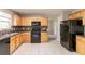 Functional kitchen featuring white tile flooring, wooden cabinets and black appliances at 4097 Rosebud Park Dr, Snellville, GA 30039
