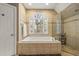 Tiled bathroom with a soaking tub under an arched window and separate glass enclosed shower at 788 Old Paper Mill Dr, Marietta, GA 30067