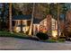 This home's exterior shines, accented by elegant lighting and a stone chimney in the evening at 11630 Mountain Laurel Dr, Roswell, GA 30075