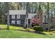 Charming two-story home with dark siding, a stone chimney, mature trees, and a lush green lawn at 11630 Mountain Laurel Dr, Roswell, GA 30075