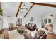 Bright living room features vaulted ceiling with wood beams, hardwood floors, and comfortable leather seating at 11630 Mountain Laurel Dr, Roswell, GA 30075