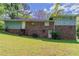 View of the back of the home showing brick and vinyl siding, a grassy yard and mature trees at 1956 Joseph Ct, Decatur, GA 30032