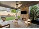 Covered patio with brick fireplace, ceiling fan, and furniture for outdoor entertaining with a landscaped backyard view at 1720 Barclay Close Nw, Atlanta, GA 30318