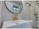 A bright bathroom with a round mirror and walk-in shower with brass fixtures at 3340 Brenda Ln, Lithia Springs, GA 30122