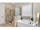 Bathroom featuring a soaking tub and a frameless glass shower with pebble flooring at 359 Woodridge Pass, Canton, GA 30114