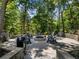 Outdoor fire pit area with gravel, stone walls, and chairs, creating a cozy gathering space in a wooded setting at 3965 Hamilton View Way, Dacula, GA 30019