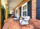 Inviting front porch with cozy chairs, red brick and black shutters, offering a relaxing outdoor seating area at 3965 Hamilton View Way, Dacula, GA 30019