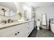 Bright bathroom features granite countertop, dual sinks, round mirrors, dark fixtures, and herringbone tile accent at 7660 Brentwood Ct, Cumming, GA 30040