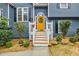 Close-up of a vibrant yellow front door adorned with a wreath, framed by white railings and manicured landscaping at 7660 Brentwood Ct, Cumming, GA 30040