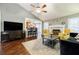 Inviting living room featuring hardwood floors, a ceiling fan, and an open layout to the breakfast bar and kitchen at 7660 Brentwood Ct, Cumming, GA 30040