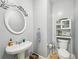 Cozy powder room featuring pedestal sink, decorative mirror, and a convenient toilet paper holder at 3800 Lake Pass Ln, Suwanee, GA 30024