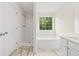 A bathroom featuring a separate shower and tub under a window, with modern fixtures and marble-patterned flooring at 5615 Crystal Hl, Stone Mountain, GA 30088