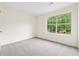A bedroom with neutral walls, carpet, and a large window letting in natural light at 5615 Crystal Hl, Stone Mountain, GA 30088
