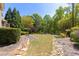 Well-maintained backyard featuring a stone walkway, mature trees, and manicured landscaping at 5055 Stefan Ridge Way, Buford, GA 30519