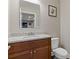 Powder room featuring a wood vanity, granite countertop, toilet, and a decorative mirror at 5055 Stefan Ridge Way, Buford, GA 30519