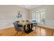 Stylish dining room with hardwood floors, modern table and chairs, wainscoting, and natural light from the shuttered window at 5055 Stefan Ridge Way, Buford, GA 30519