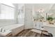 Bright bathroom features a soaking tub under a window and white vanity at 2305 Stonevalley Ct, Cumming, GA 30041