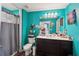 A bright bathroom featuring teal walls, a white vanity, and coordinated accessories for a lively feel at 2051 Wildflower Way, Conyers, GA 30012