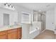 Bright bathroom featuring a large tub, glass shower, and wood cabinets at 5480 Beaver Ridge Drive Dr, Cumming, GA 30040