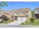 View of a two-story home with tan siding, brick accents, two-car garage, and manicured lawn at 5480 Beaver Ridge Drive Dr, Cumming, GA 30040