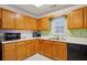 This is a bright kitchen featuring oak cabinets, black appliances, and double stainless steel sink under a window at 2828 Marksman Trl, Austell, GA 30106