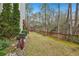 View of the backyard with grassy lawn, stone wall, landscaping, and tall trees at 3887 Hickory Manor Dr, Suwanee, GA 30024