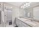 Bright bathroom featuring a double sink vanity, granite countertop, large mirror, and tiled floors at 3887 Hickory Manor Dr, Suwanee, GA 30024