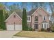 Charming two-story brick home with well-maintained landscaping and a two-car garage on a sunny day at 3887 Hickory Manor Dr, Suwanee, GA 30024