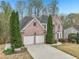 Brick two-story home with well-manicured landscaping, mature trees, and a two-car garage at 3887 Hickory Manor Dr, Suwanee, GA 30024